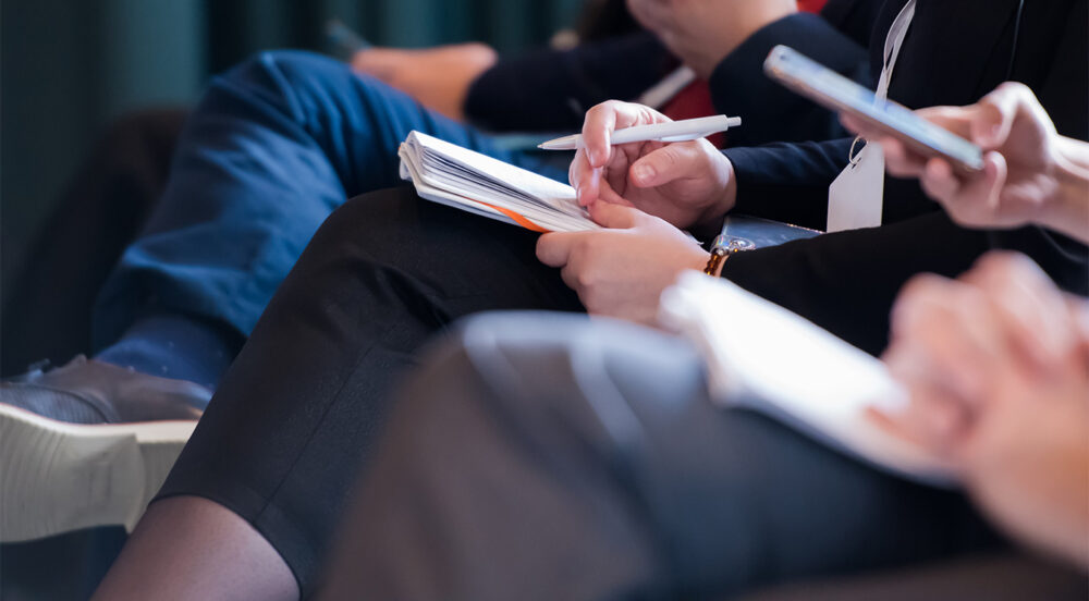 closeup shot of reporters taking notes on cybersecurity conference