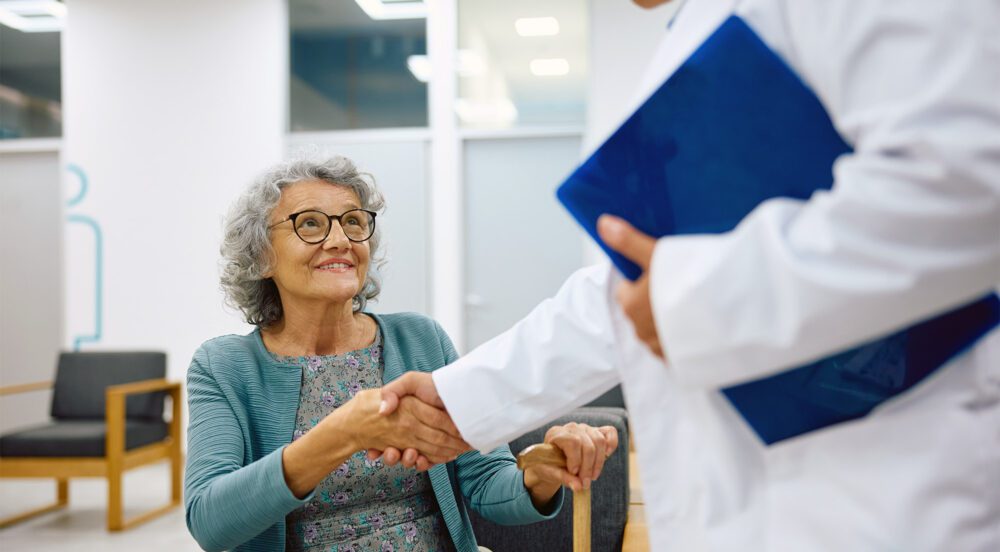 Senior woman greets her doctor in waiting room at medical clinic.